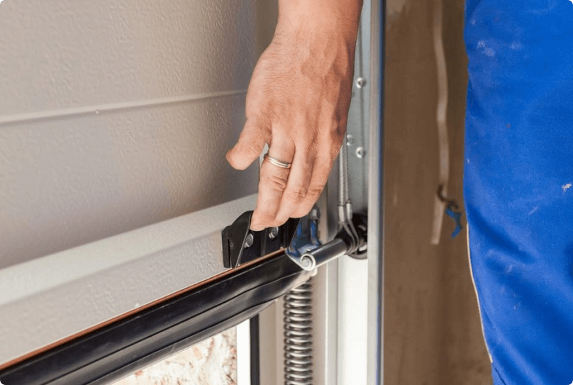 A person is holding the door handle of their garage.