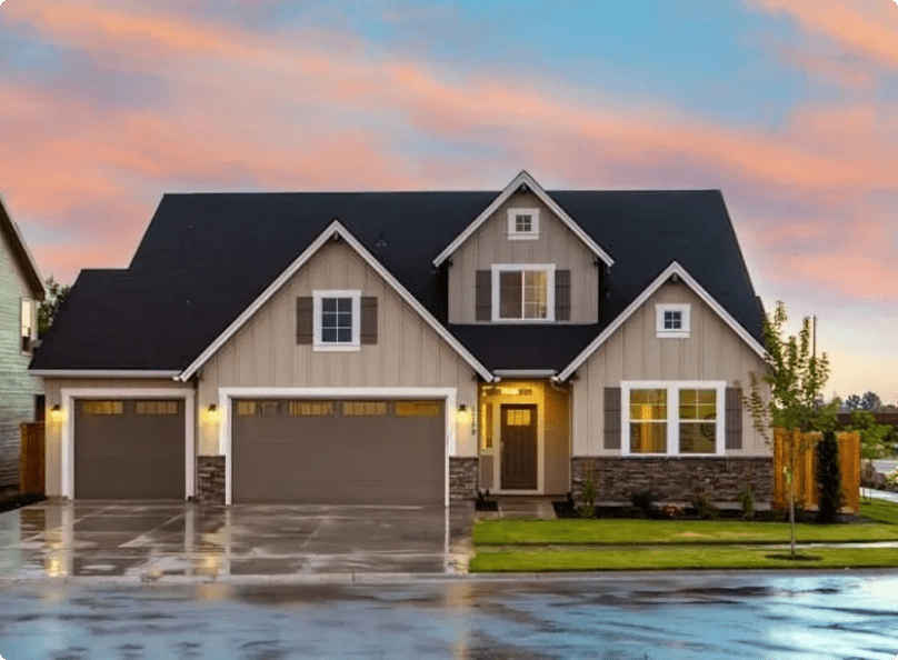 A house with a garage and water in front of it.