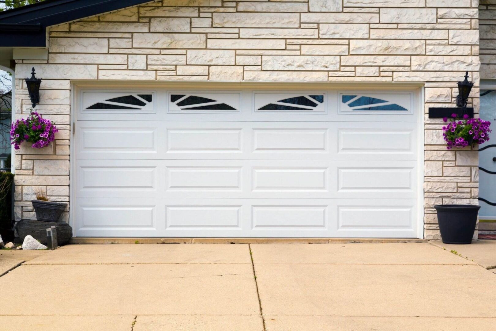 A white garage door sitting in front of a brick wall.